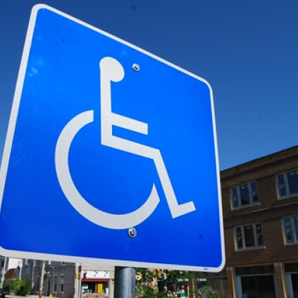 Slika prometnega znaka, na katerem je narisana mednarodna oznaka za dostopnost invalidom.