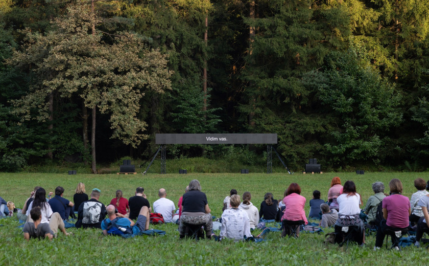 Obiskovalci pred črnim ekranom, na katerem piše Vidim vas.