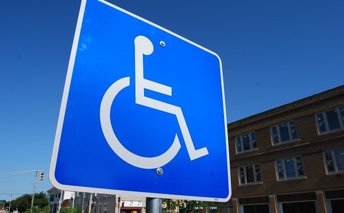 Slika prometnega znaka, na katerem je narisana mednarodna oznaka za dostopnost invalidom.