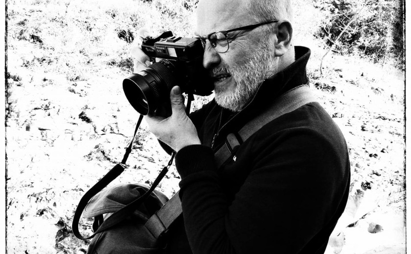 črnobela fotografija fotografa jožeta suhadolnika, ki kuka skozi kukalo svojega fotoaparata